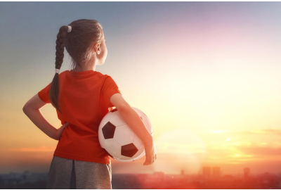 girl holding a football and looking at the sky